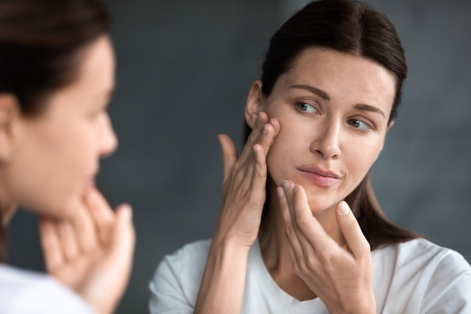 Brunette woman examining her skin in the mirror