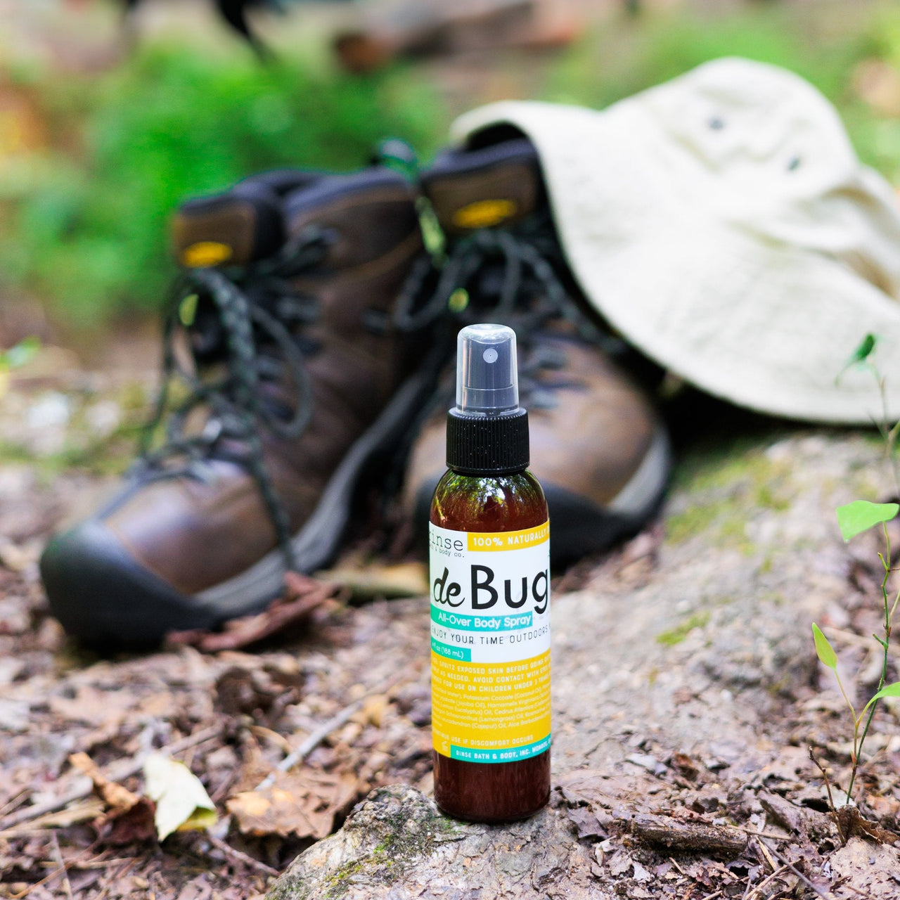 DeBug DEET-free bug repellent beside hiking boots — garden and outdoor stores