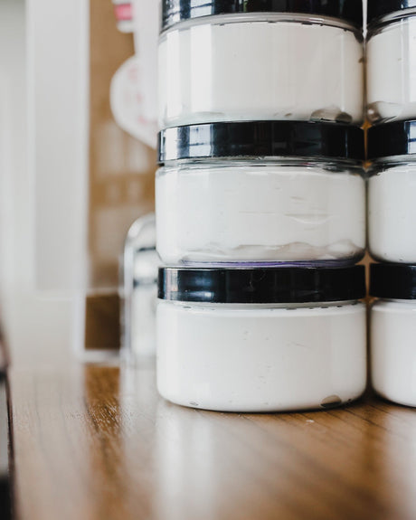 Almond & Honey body spread in its tub with the lid off — a thick shea-butter moisturizer for skin that drinks lotion and asks for more. Rinse Bath & Body Co.
