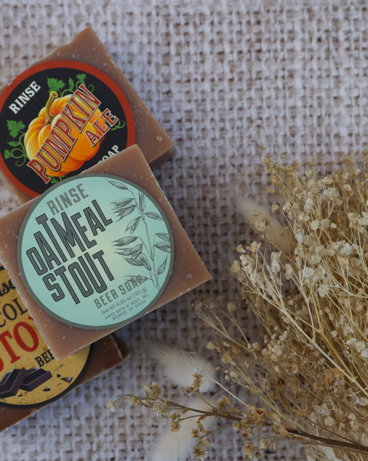 Oatmeal Stout bar soap showing its oat-flecked top and dark poured base. Rinse Bath & Body Co.