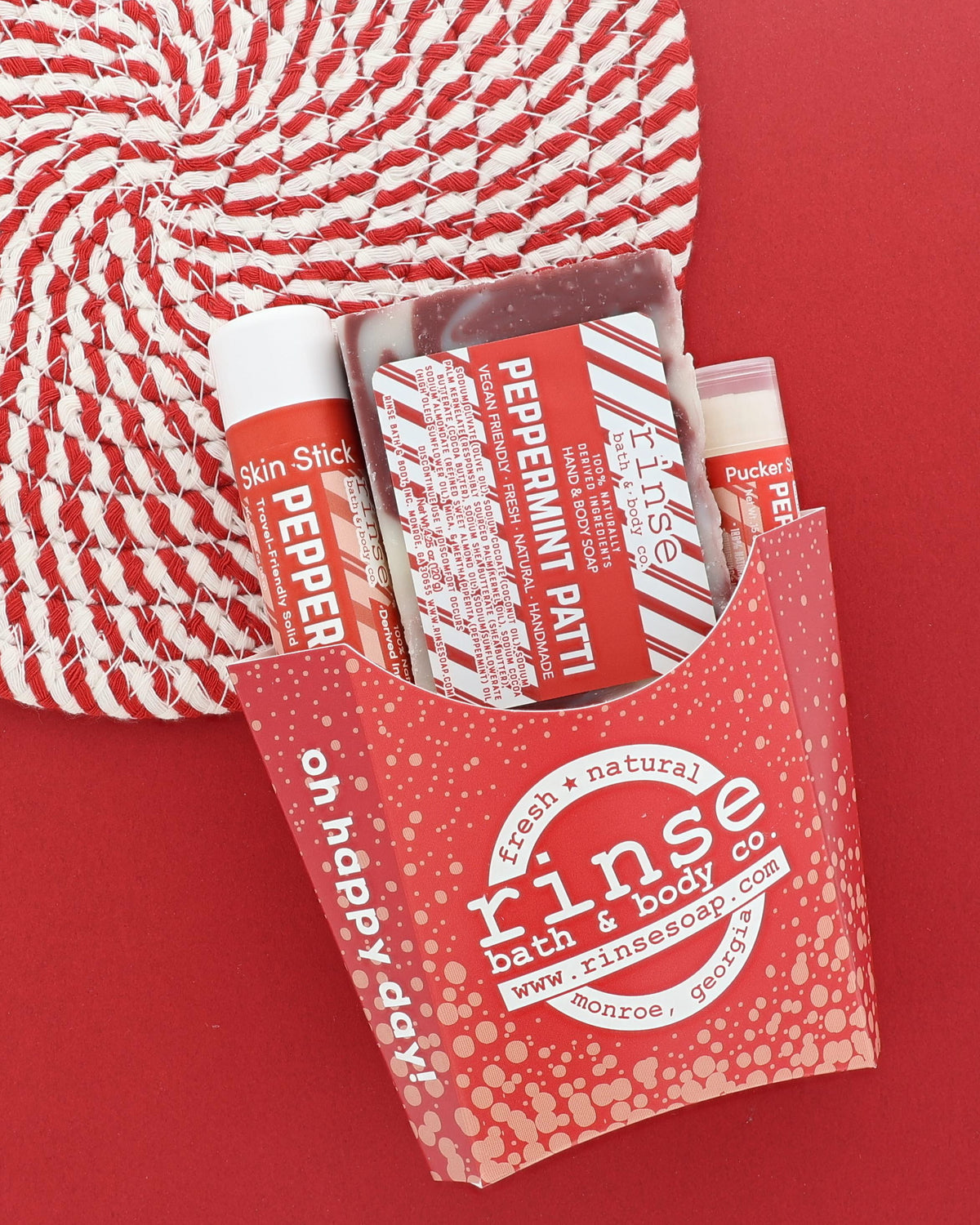 Peppermint Patti gift set in a red fry carton with soap, Skin Stick and Pucker Stick on a candy-stripe placemat on red
