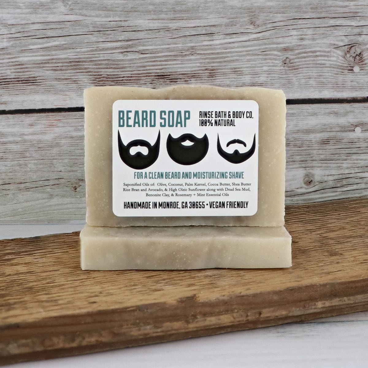 Two mini Beard Soap bars stacked on reclaimed wood — teal beard icons against gray plank wall