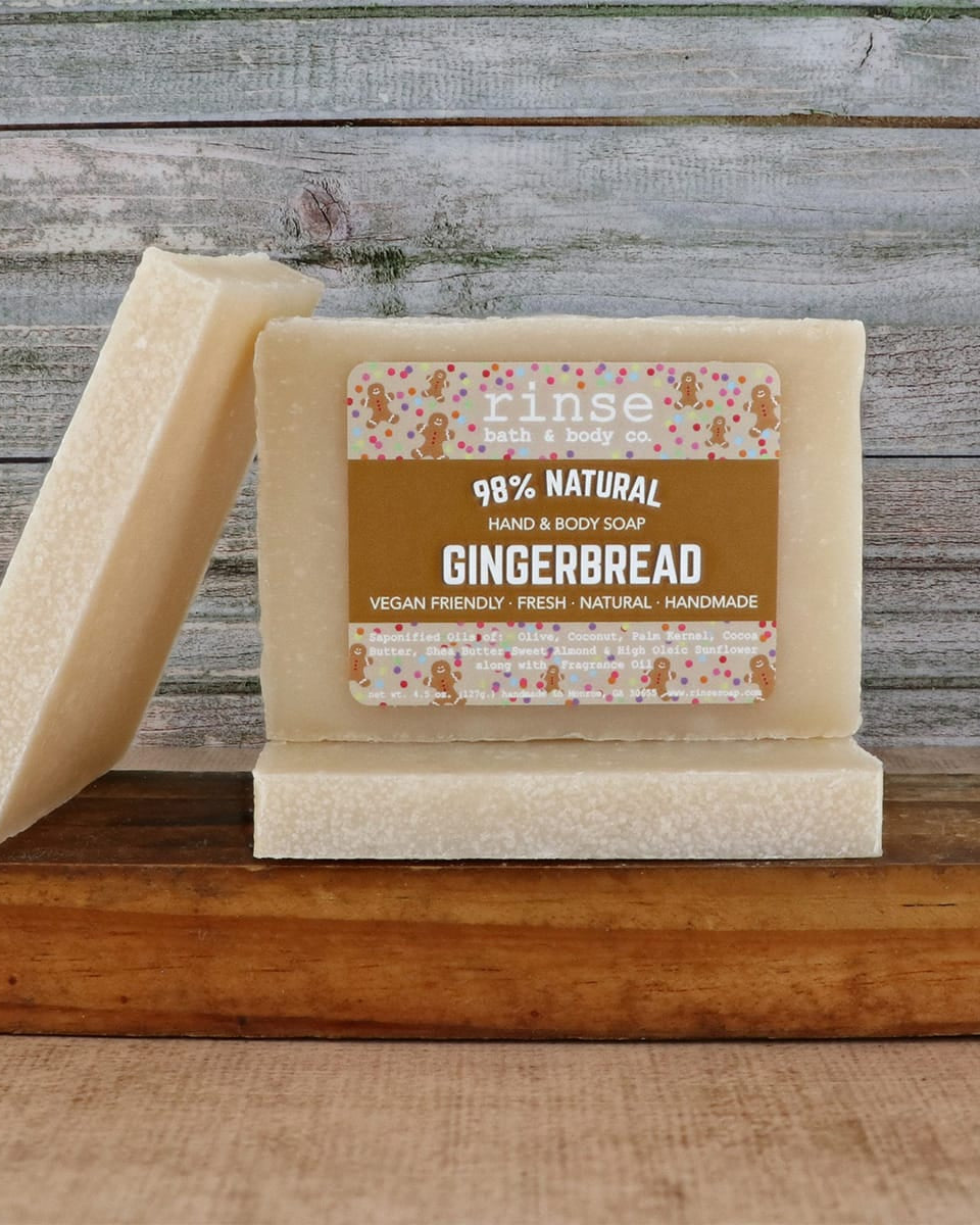 Two Gingerbread soap bars leaning on polished wood — speckled cream bars against weathered plank wall