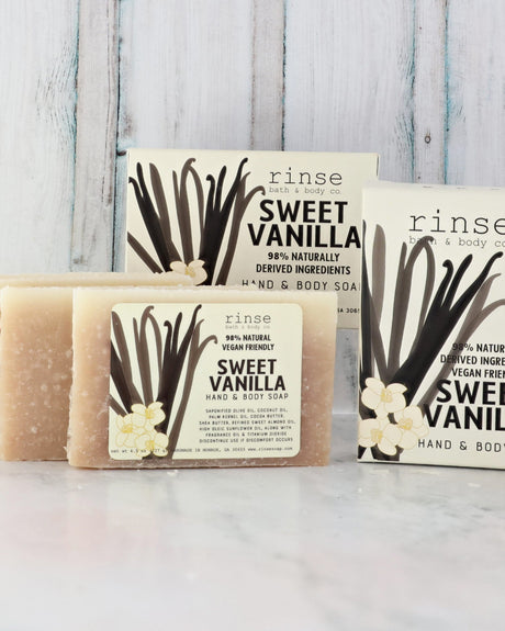 Sweet Vanilla mini soaps and white cartons on marble — blue-washed wood planks glowing behind