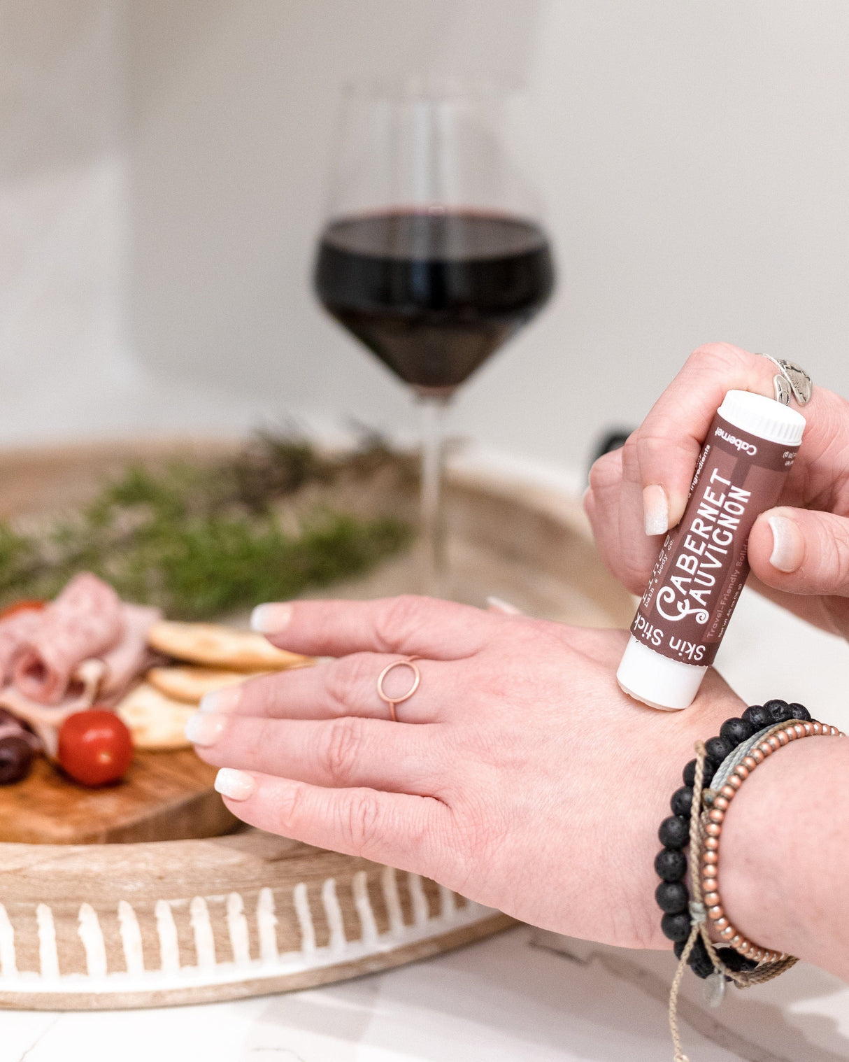 Cabernet solid lotion stick smoothed onto skin — deep red wine and dark berry in a twist-up bar of concentrated moisture. Rinse Bath & Body Co.