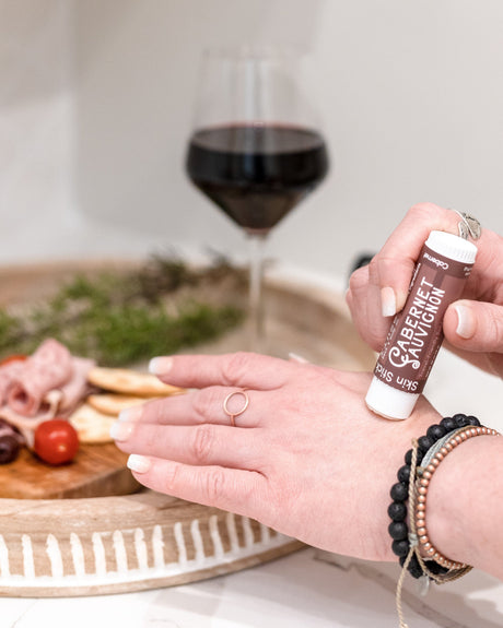 Cabernet solid lotion stick smoothed onto skin — deep red wine and dark berry in a twist-up bar of concentrated moisture. Rinse Bath & Body Co.