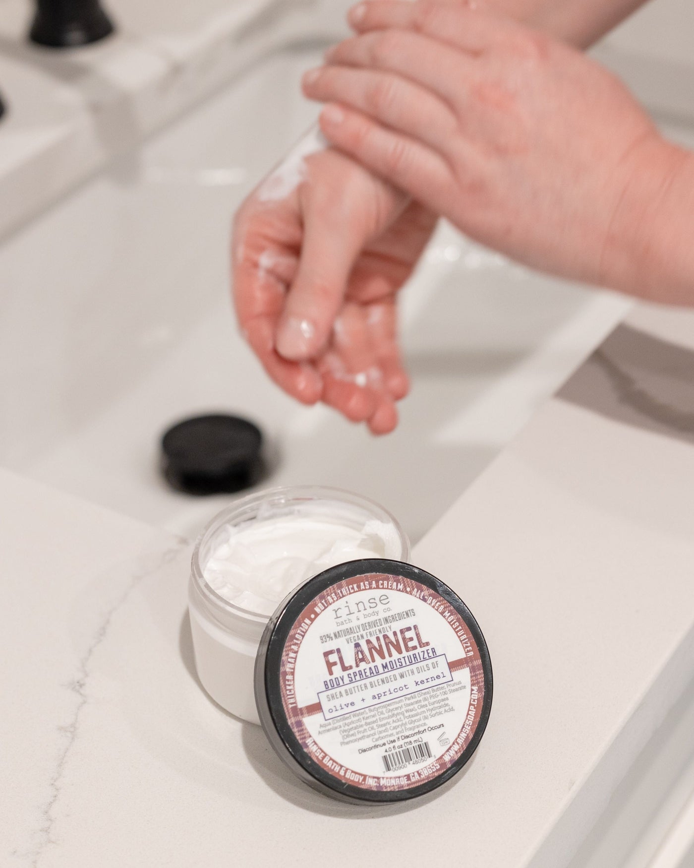 Flannel body spread scooped and worked into skin — rich butter that finishes soft, not greasy. Rinse Bath & Body Co.