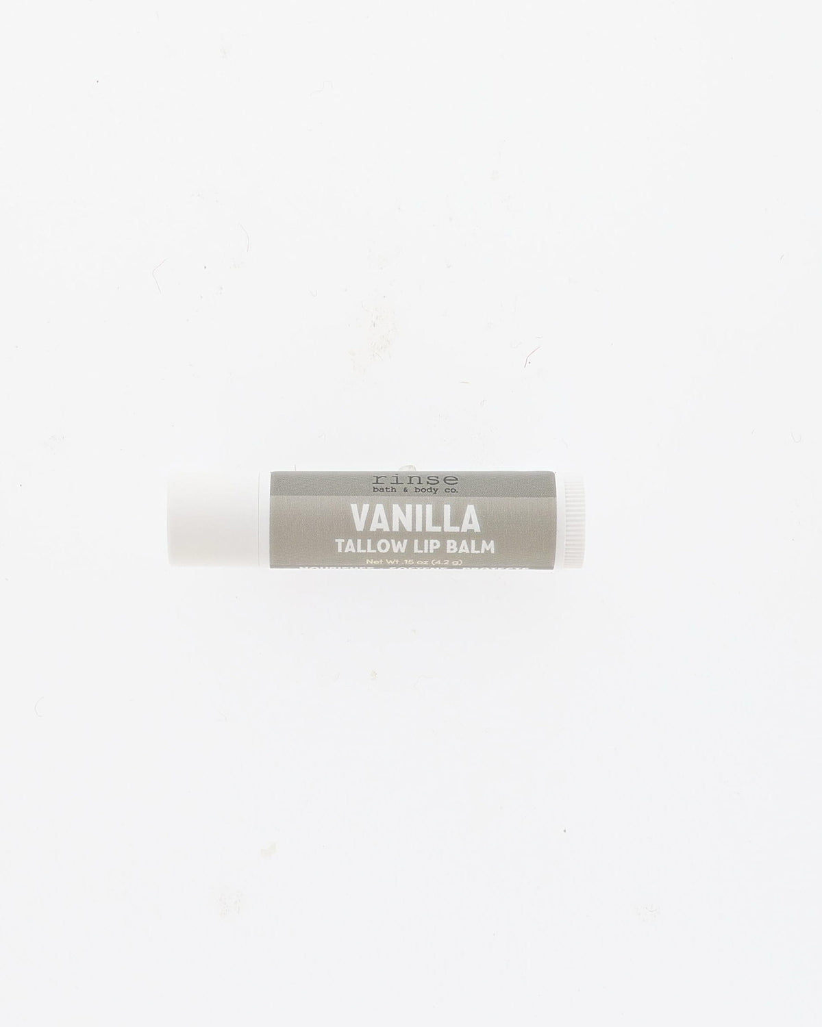 Vanilla Tallow Lip Balm tube with grey label and white cap lying on a plain white background
