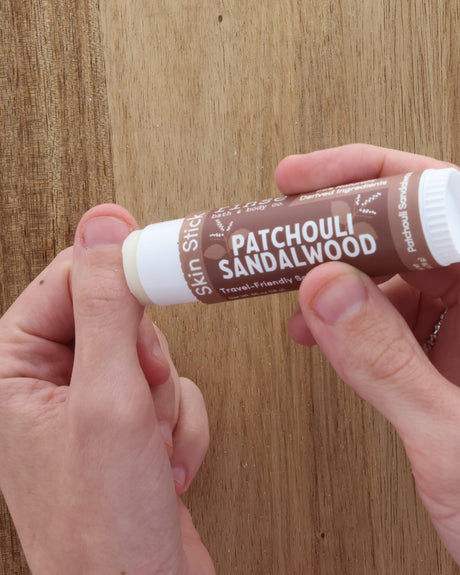 Patchouli Sandalwood solid lotion stick styled warm and close — earthy patchouli over sandalwood in a twist-up bar of concentrated moisture. Rinse Bath & Body Co.