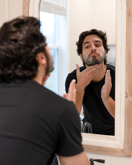 Rinse Conditioning Beard Balm tin open on a weathered surface, balm surface smoothed from use — a daily grooming step, not a treatment. Rinse Bath & Body Co.