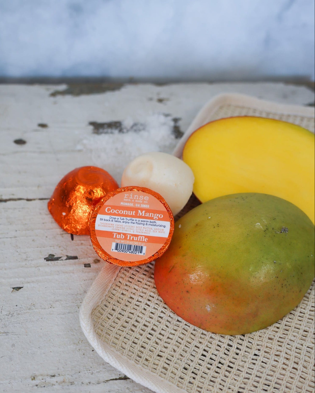 Coconut Mango truffle on a wooden surface with mangoes