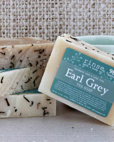 Earl Grey Tea Soap stack on coarse burlap — tea-flecked cream bars with teal label in warm light