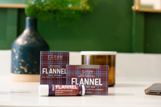 Rinse Flannel hand and body soap and candle styled on a shelf with a vase