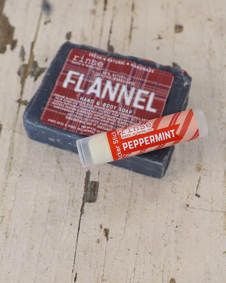 Dark Flannel soap with Peppermint Pucker Stick across its corner — weathered whitewashed wood in rustic light