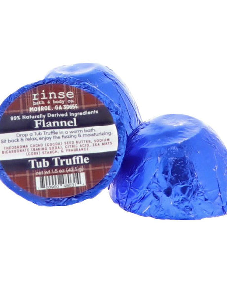 Flannel tub truffle showing its cocoa-butter centre — a bath bomb that moisturises as it fizzes, in sharp musk and clean cotton. Rinse Bath & Body Co.