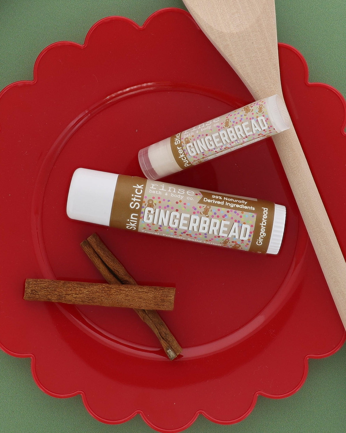 Gingerbread Skin Stick and Gingerbread Pucker Stick on a red scalloped plate with cinnamon sticks and a wooden spoon