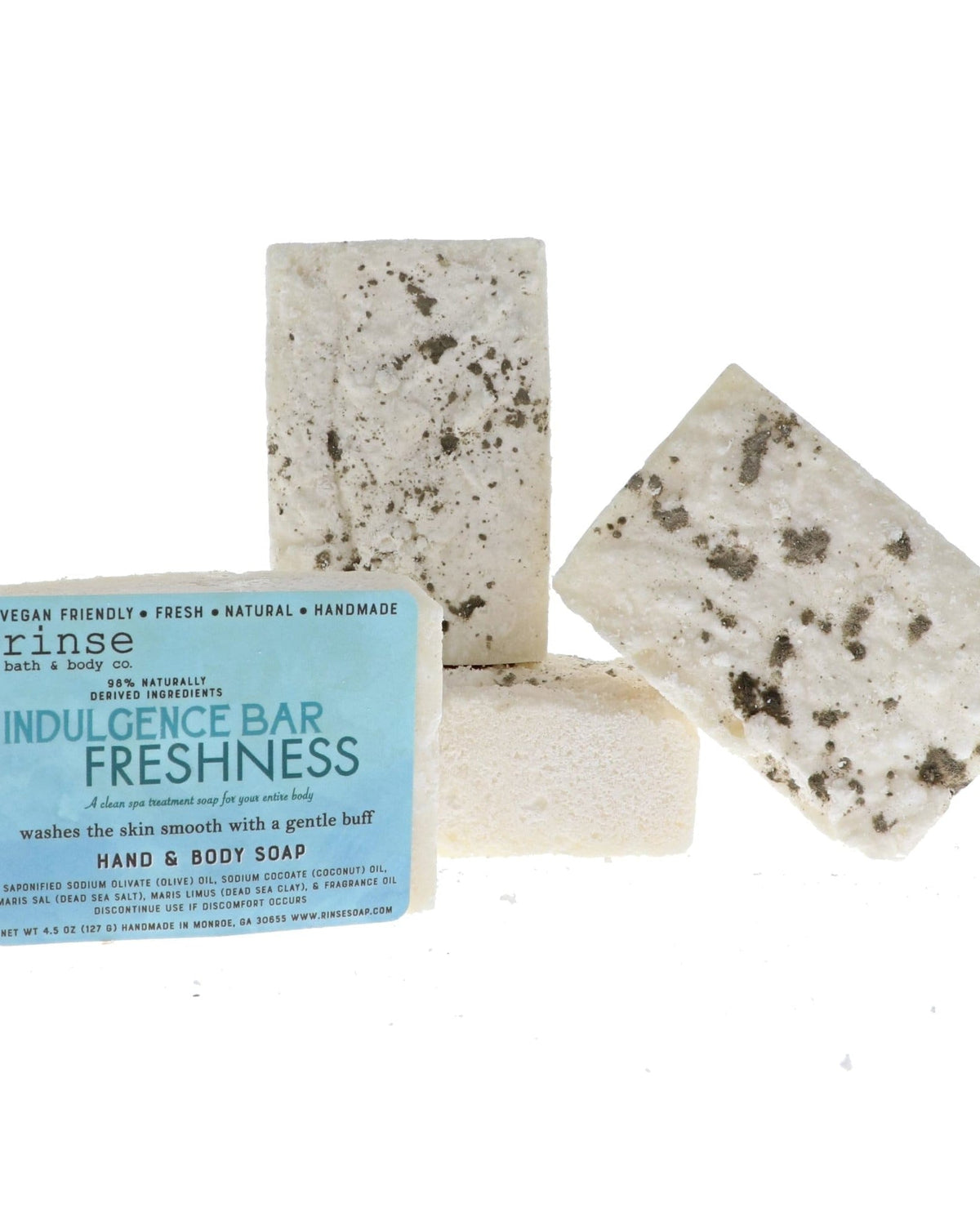 Four Indulgence Bar Freshness soaps clustered on bright white — creamy bars flecked with dark mineral clay and salt