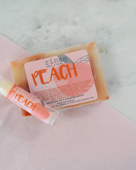 Peach soap and Peach Pucker Stick rest on pink tissue — white marble veins soft underneath