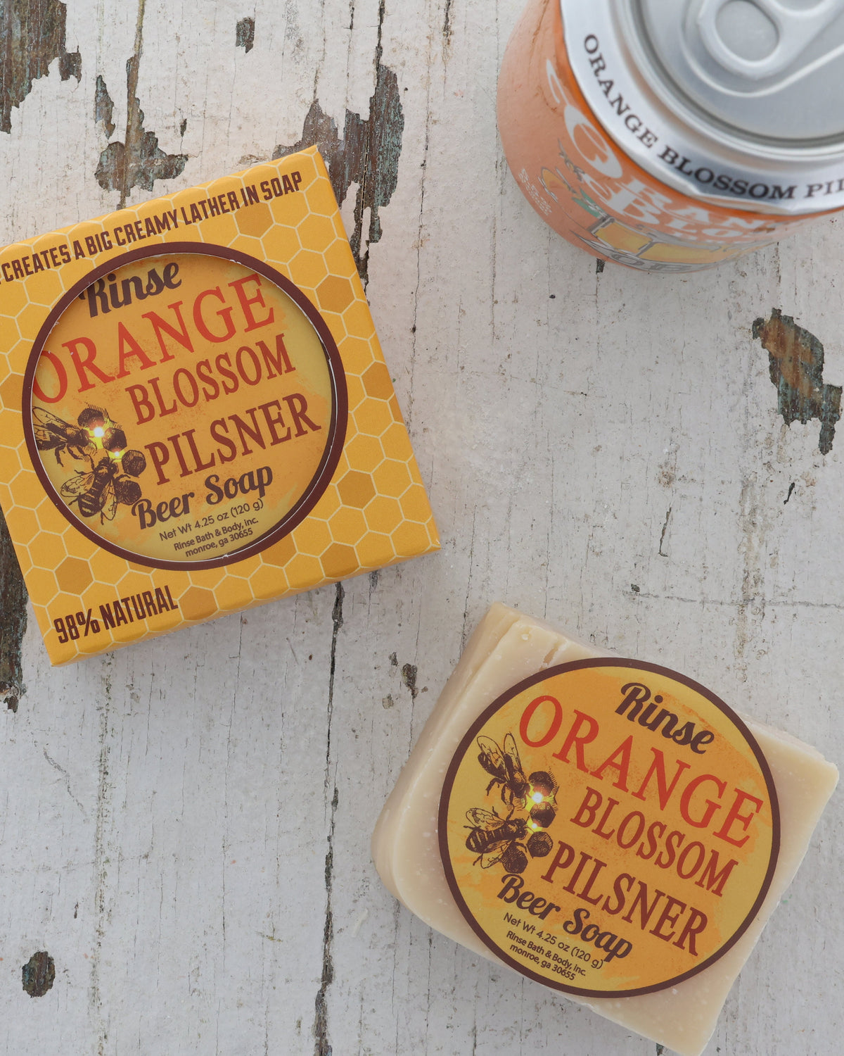 Orange Blossom Pilsner soap beside honeycomb yellow box — orange beer can corner on weathered white wood