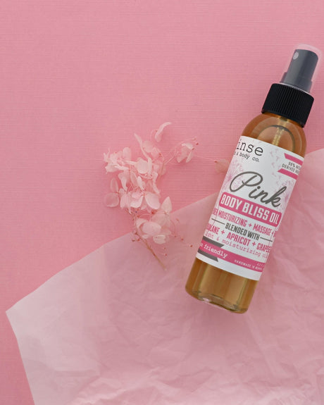 Pink Body Bliss oil bottle on a pink ground with dried florals