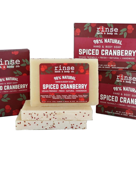 Spiced Cranberry mini soap bars stacked before burgundy cranberry-vine cartons — seed-flecked cream bars, warm holiday spice scent