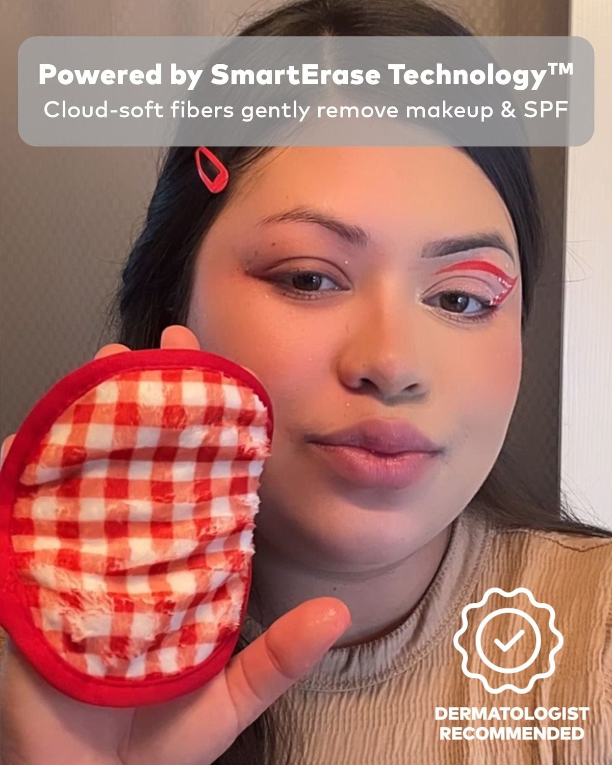Hand holding red gingham MakeUp Eraser cloth to cheek mid-cleanse — strawberry-set cloth removing makeup with just water