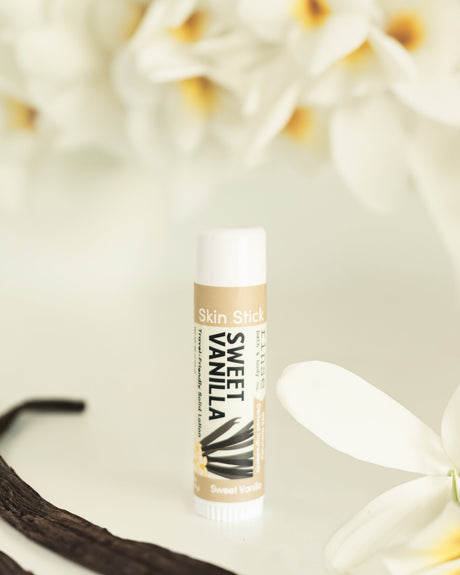 The Sweet Vanilla solid lotion stick styled on a warm neutral surface — a twist-up bar of concentrated vanilla moisture for dry hands, elbows and heels. Rinse Bath & Body Co.