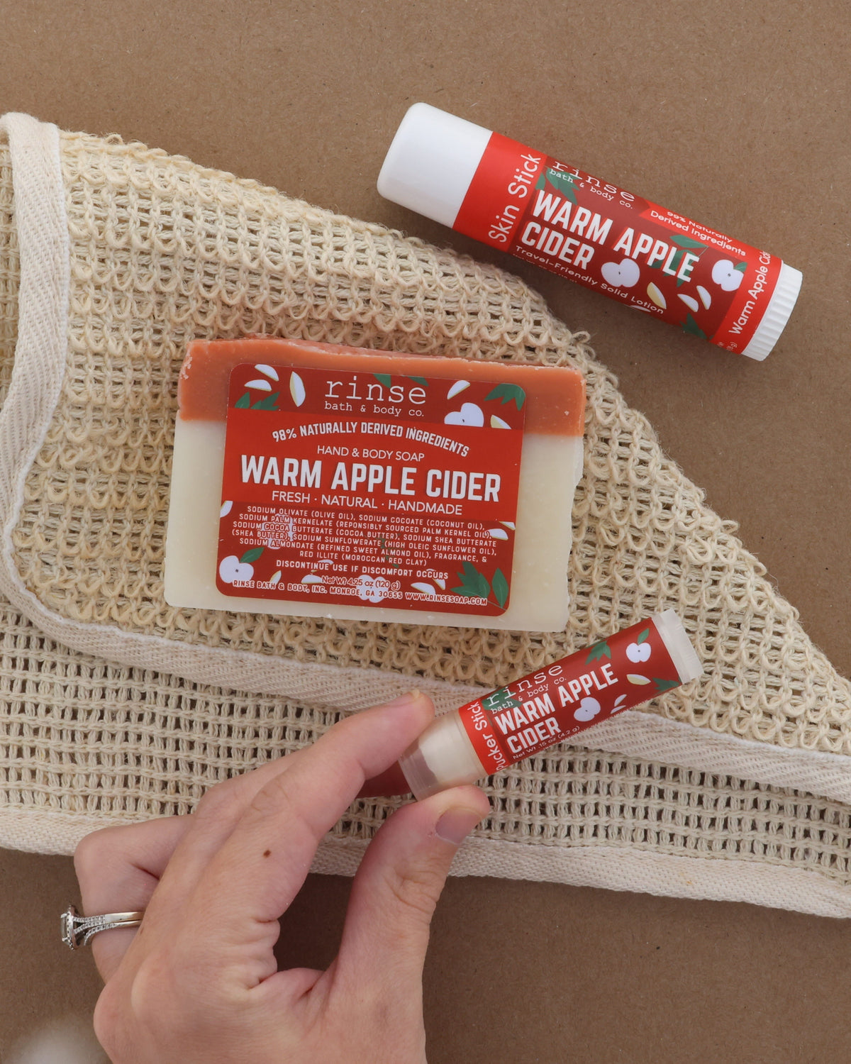 Hand holding Warm Apple Cider soap with rich lather worked up — cocoa-butter bar in use