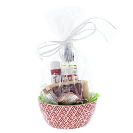 Spiced Cranberry holiday set wrapped in cellophane inside a red diamond bowl — green tissue and white ribbon bow