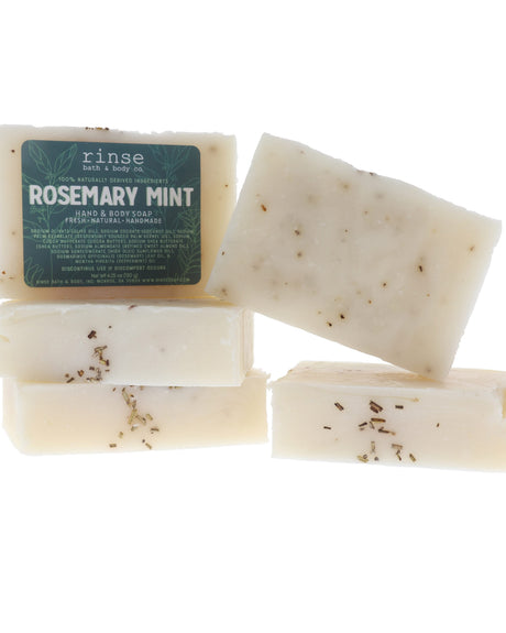 Rosemary Mint soap stack shows herb-flecked cream bars — dark green label on clean bright white