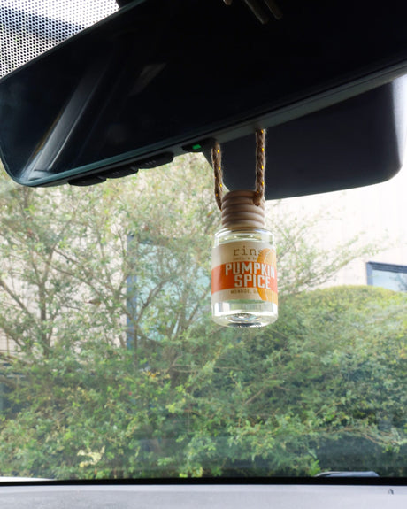 Pumpkin Spice car diffuser, wooden cap on its cord — nutmeg, clove and brown sugar that scents the car for weeks on one fill. Rinse Bath & Body Co.