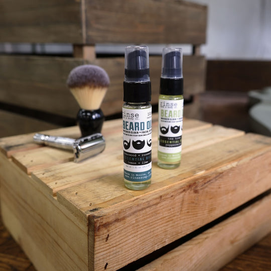 2 beard oils on table with beard brush and razor