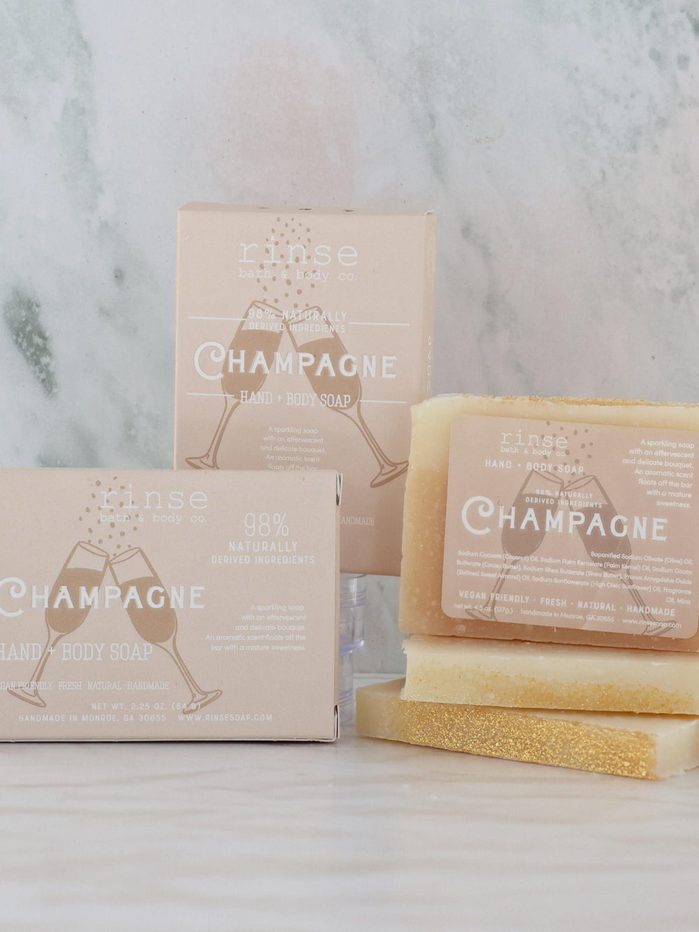 Champagne bars and tan boxes resting on cool marble — gold glitter tops and a delicate sparkling scent