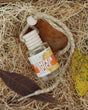 Pumpkin Spice car diffuser with wooden cap and braided cord, resting in straw beside autumn leaves