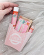 Hand lifting the Nutcracker Skin Stick from a pink fry carton with soap and Pucker Stick on sparkly grey tulle