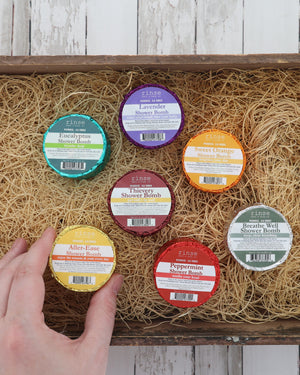 Eucalyptus shower bomb with six other scents including Lavender, Thievery and Breathe Well in a crate of excelsior