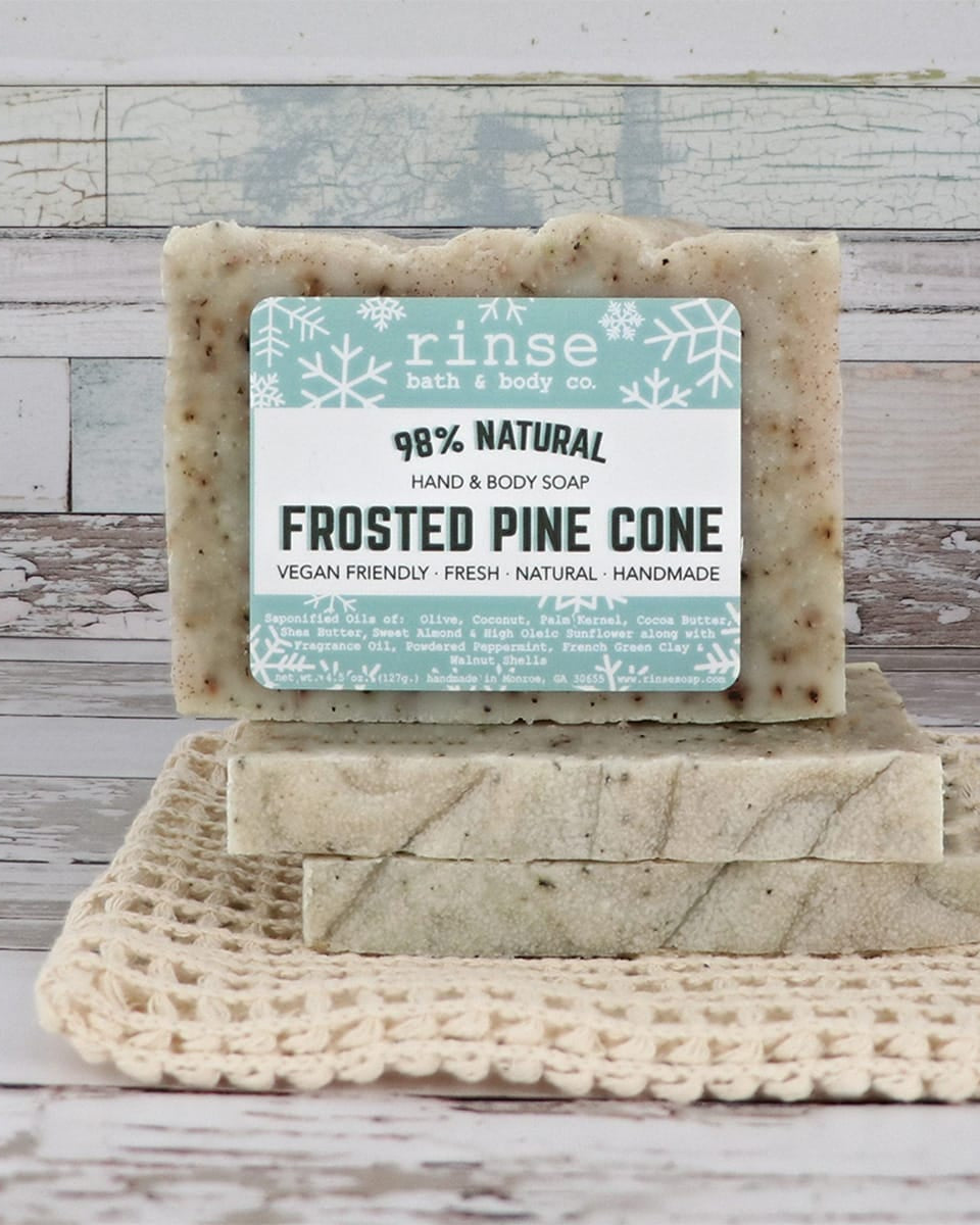 Frosted Pine Cone mini bars stacked on cream crochet over weathered wood — botanical flecks in cozy daylight