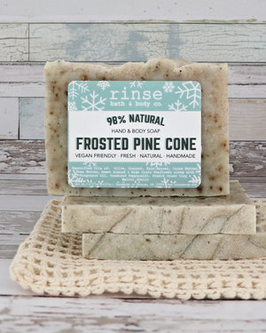 Frosted Pine Cone mini bars stacked on cream crochet over weathered wood — botanical flecks in cozy daylight