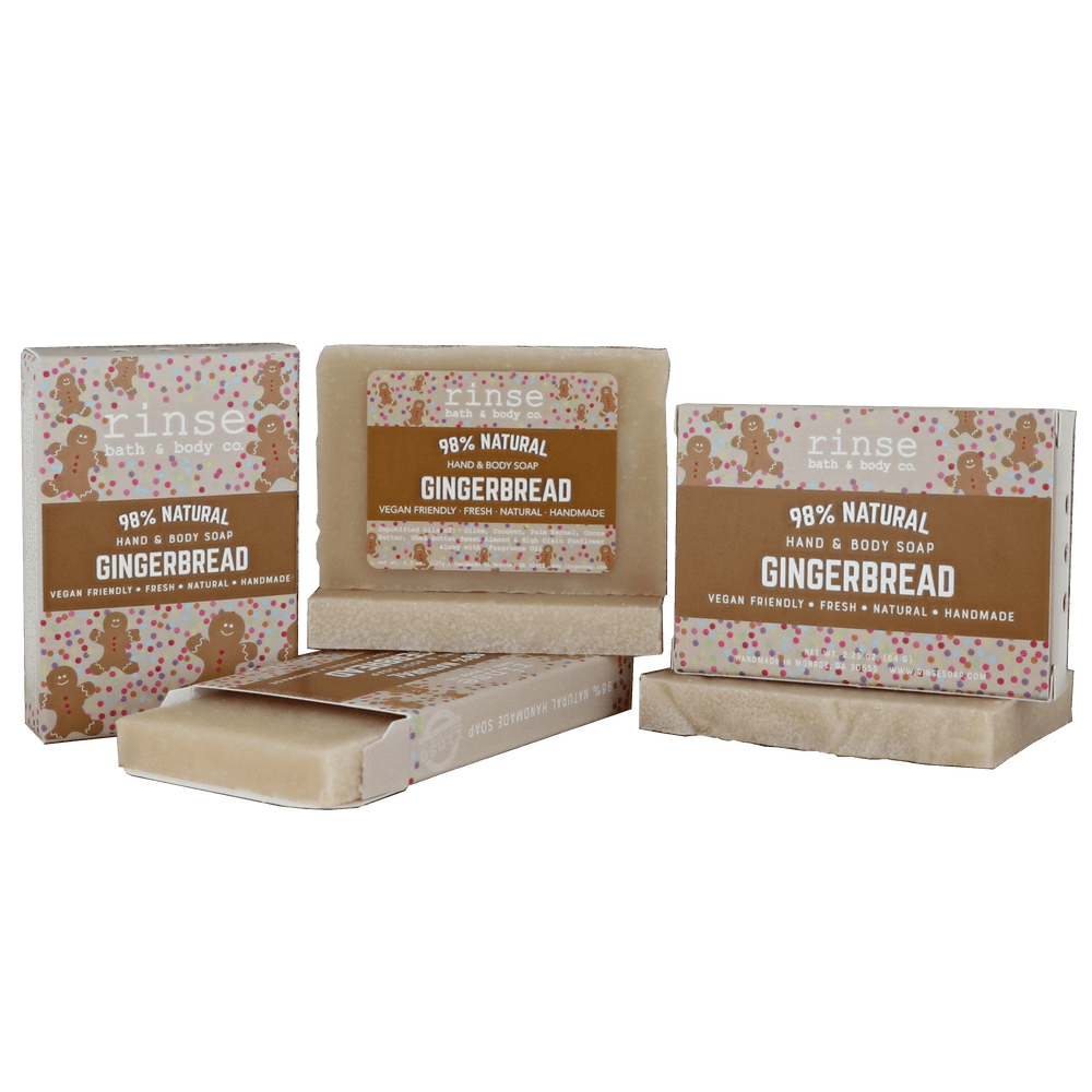 Gingerbread mini bar sliding from its illustrated carton on deep green — creamy textured soap in studio light