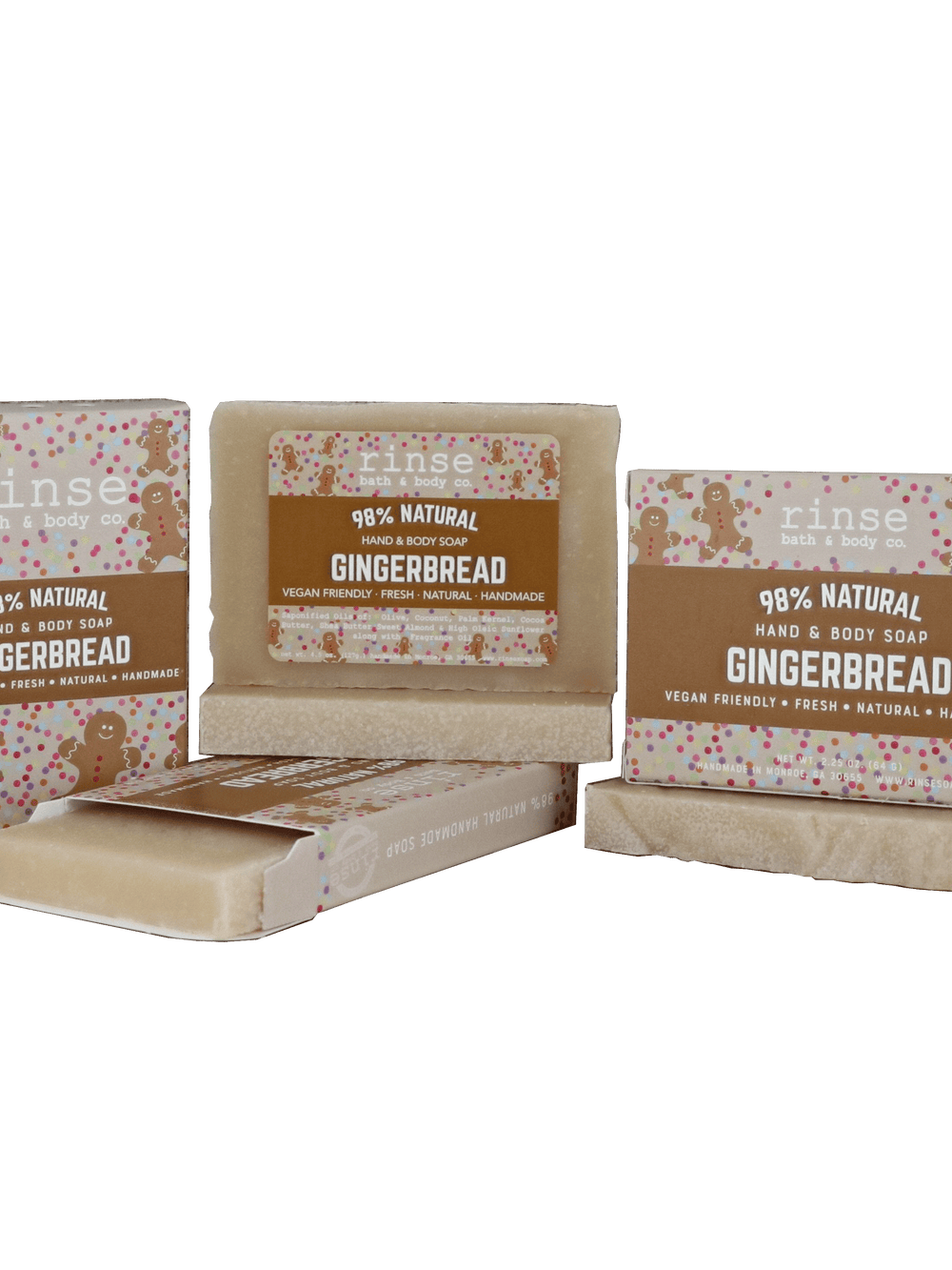 Gingerbread mini bar sliding from its illustrated carton on deep green — creamy textured soap in studio light