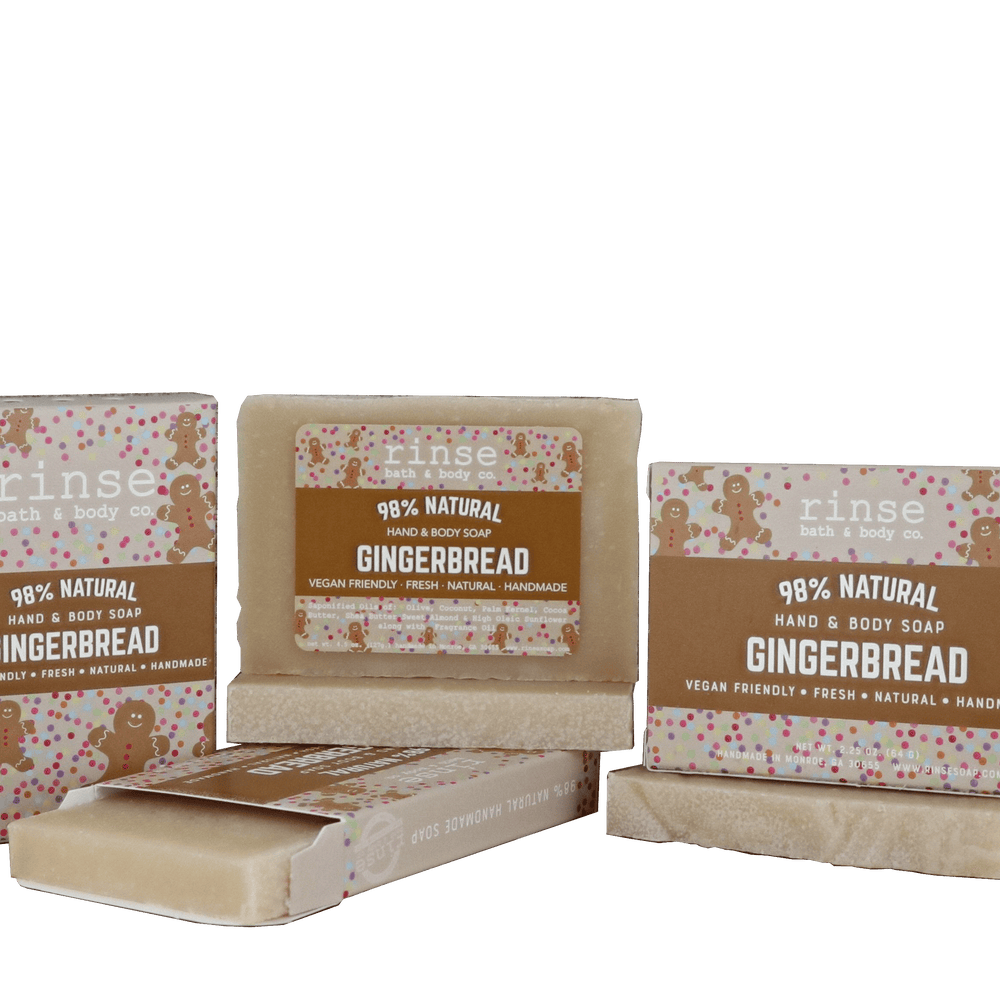 Gingerbread mini soap bars and cartons clustered on forest green — warm brown sleeves with gingerbread art