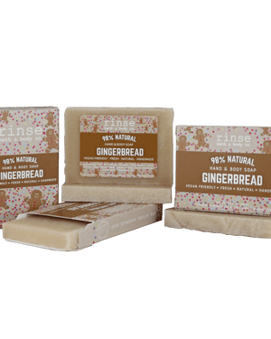 Gingerbread mini soap bars and cartons clustered on forest green — warm brown sleeves with gingerbread art