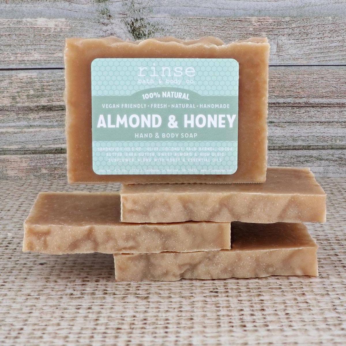 Labeled Almond & Honey bar standing on stacked bars against rustic wood and burlap — warm honey and almond for a moisturizing wash