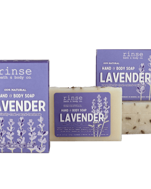 Two purple Lavender soap boxes and a flecked cream bar resting on deep green — botanical buds catching soft studio light