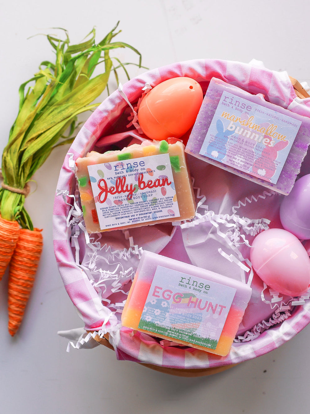 Marshmallow Bunnies soap nests in a gingham Easter basket — colorful eggs and twine carrots on white