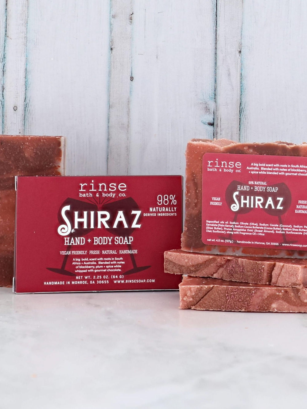 Shiraz soap bars and red box on marble before weathered blue wood — bold blackberry plum and chocolate