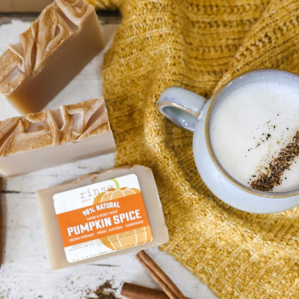 Pumpkin Spice bars flat-laid with a cinnamon-dusted latte, cinnamon sticks and a mustard knit sweater — nutmeg, clove and brown sugar, the scent inside the fry-box gift set. Rinse Bath & Body Co.