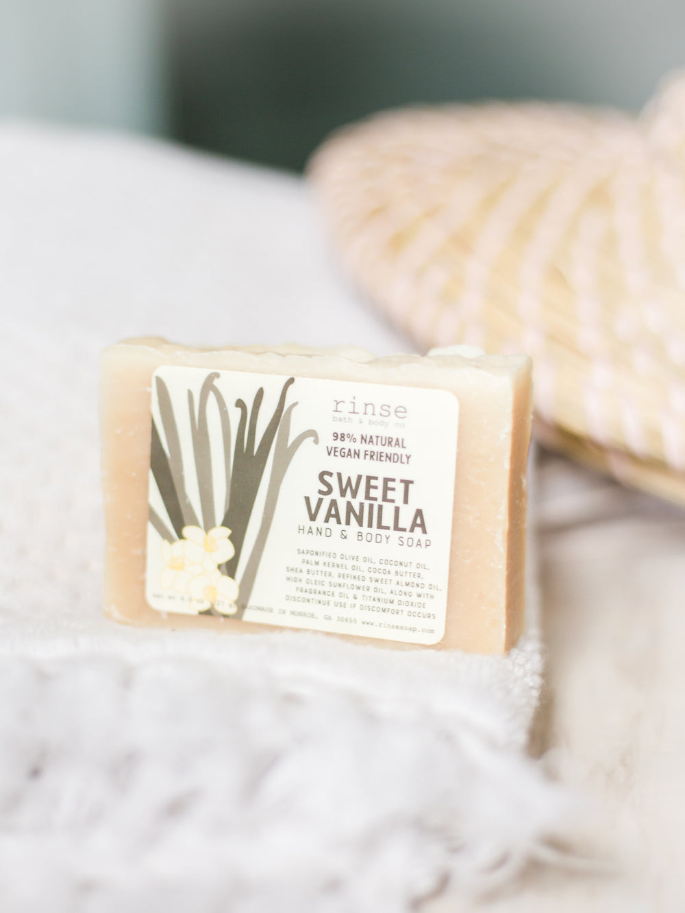 Labeled Sweet Vanilla soap bar on fringed white towel — airy bathroom light and soft natural fibers