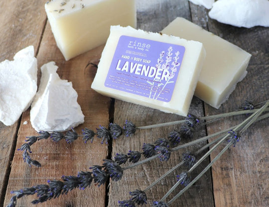 Lavender soap on wooden table next to lavender flowers