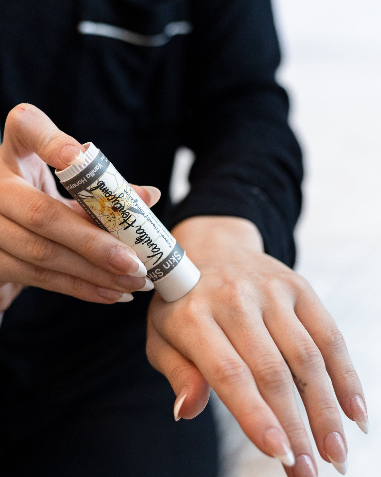 Vanilla Honeycomb solid lotion stick in use, twisted up and smoothed on by hand — warm vanilla and honey in a pocket-sized bar. Rinse Bath & Body Co.